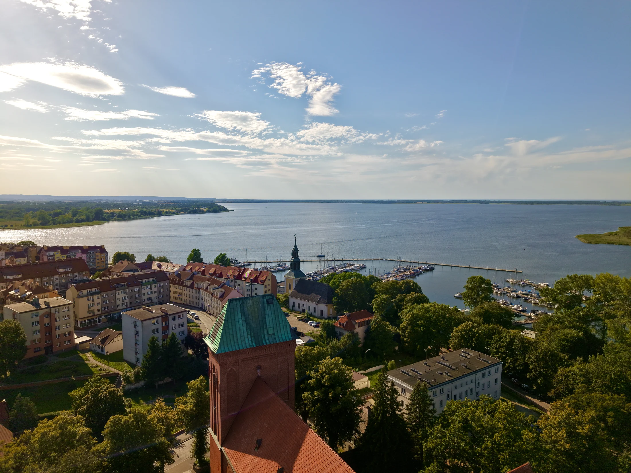 Dachy zabudowań na pierwszym planie i szeroki akwen w tle.