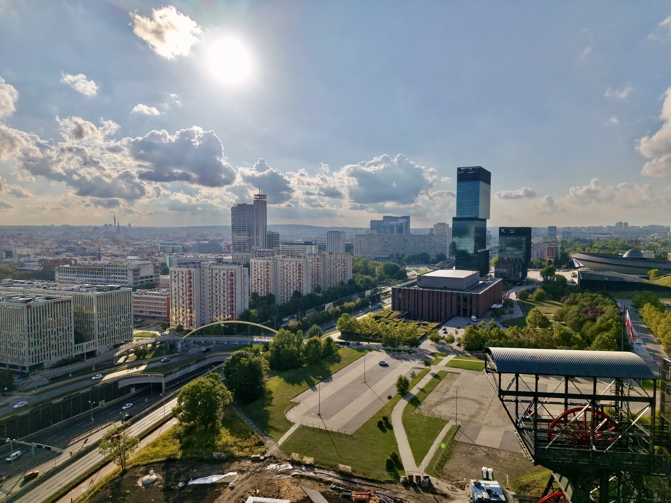 Szeroka panorama miasta z nowoczesną zabudową, drogami i zielenią.
