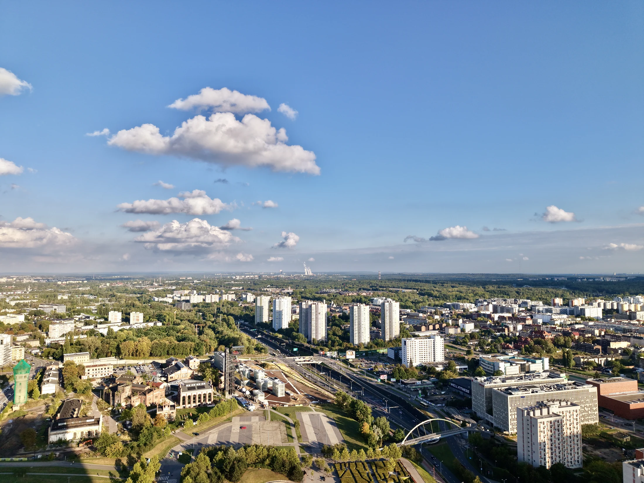 Miejska panorama z wielopiętrową zabudową, ulicami i zielenią.