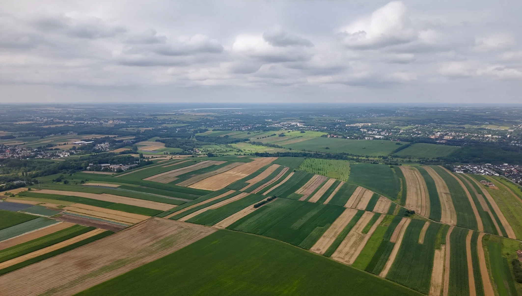 Pasy pól i zieleni tworzące geometryczny krajobraz widziany z drona.